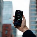 Mies pitää kädessään puhelinta, jonka näytöllä pyörii Speedtest-sovellus internet-yhteyden nopeuden mittaamiseen.