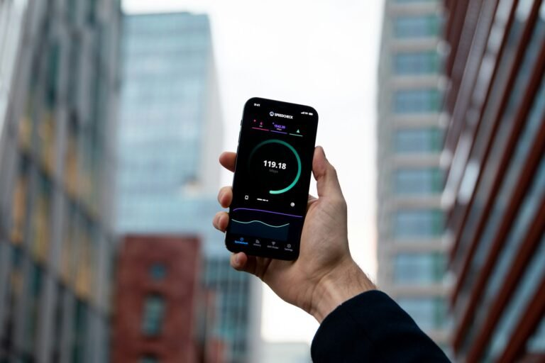 Mies pitää kädessään puhelinta, jonka näytöllä pyörii Speedtest-sovellus internet-yhteyden nopeuden mittaamiseen.
