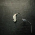 Hopeanharmaa korvantauskuulokoje, ohut letku ja silikoninen tulppa tummalla teksturoidulla pinnalla.