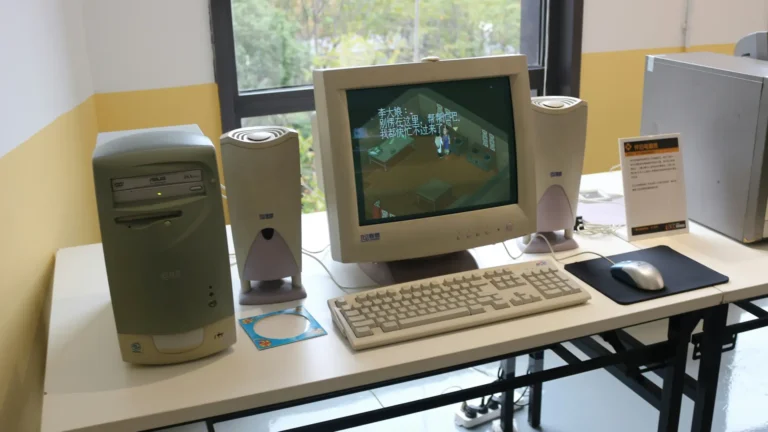 Beige pöytäkoneen kokoonpano valkoisella työpöydällä, tornikotelo, CRT-näyttö jossa kiinankielinen peli, kaksi kaiutinta, beige näppäimistö ja hiiri ikkunan edessä.