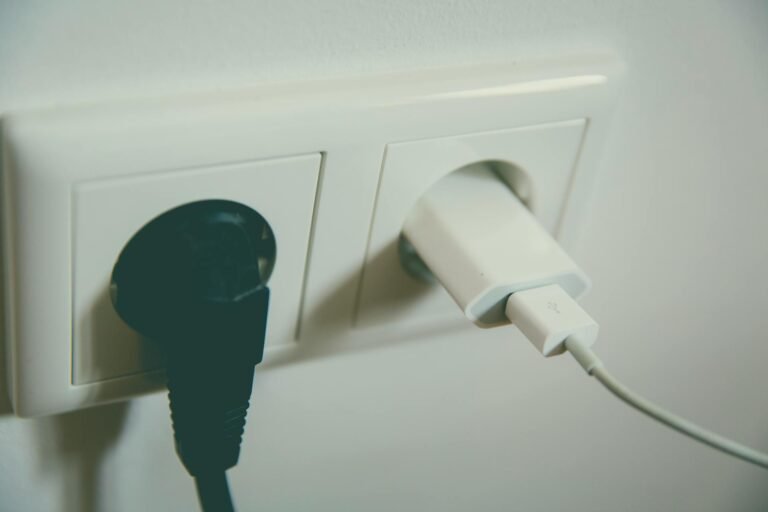Puhelimen laturi ja tietokoneen virtajohto kytkettynä pistorasiaan, esimerkki kodin viihde-elektroniikan virrankulutuksesta.
